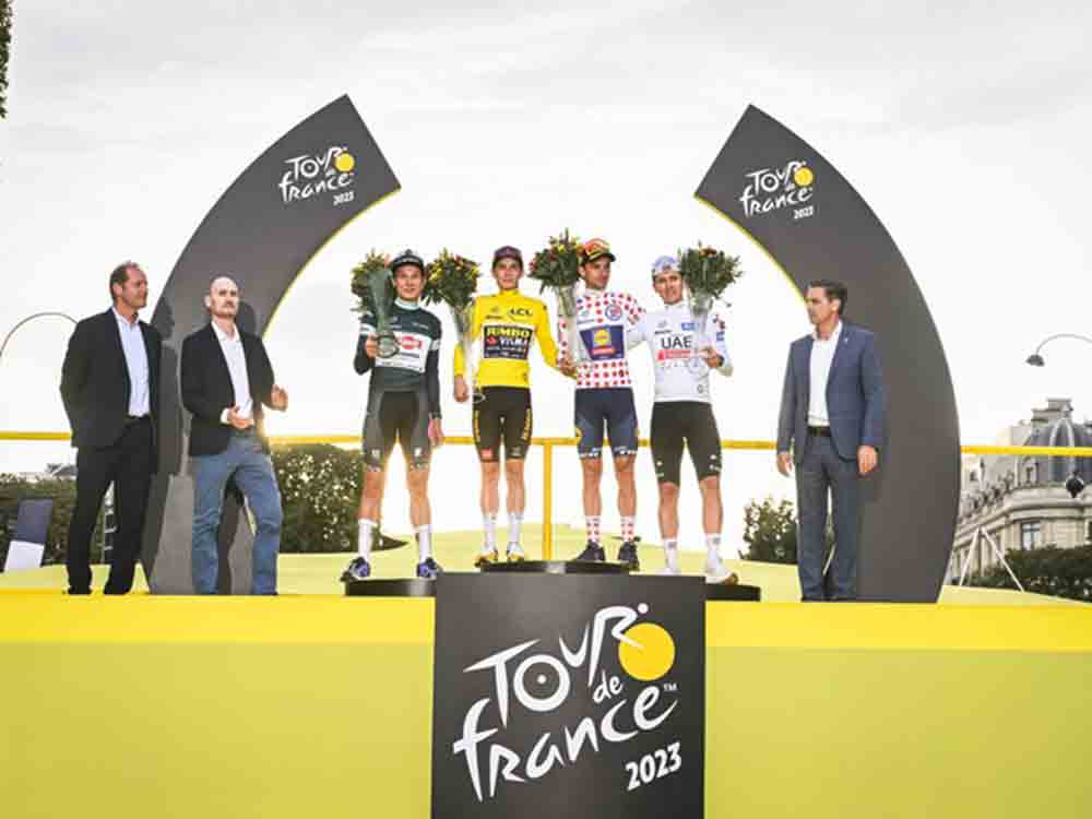 Tour de France Sieger rollt in Begleitung des noch getarnten Škoda Superb Combi ins Ziel und erhält von Škoda Design entworfene Trophäe